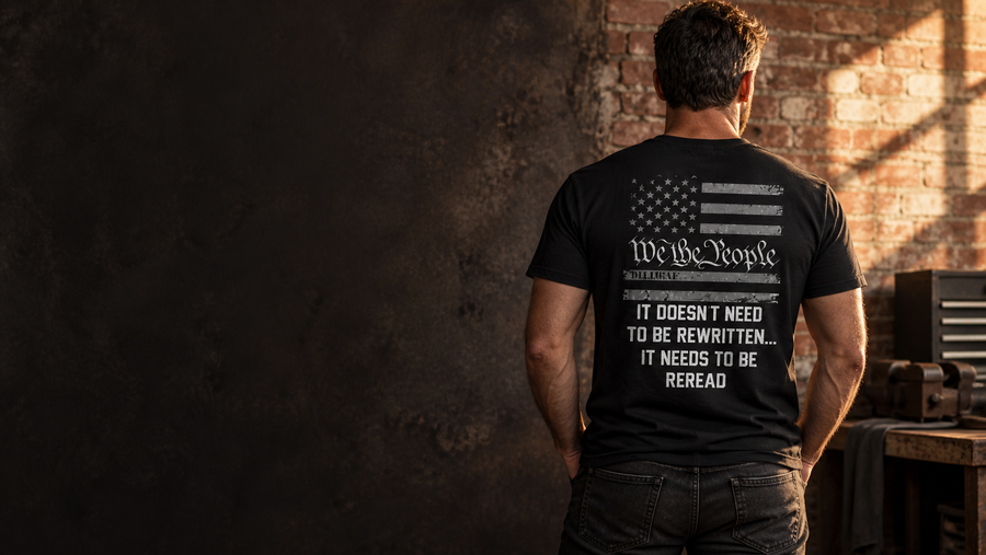 Man wearing the Dilligaf We the People black shirt, back view in a sunlit workshop